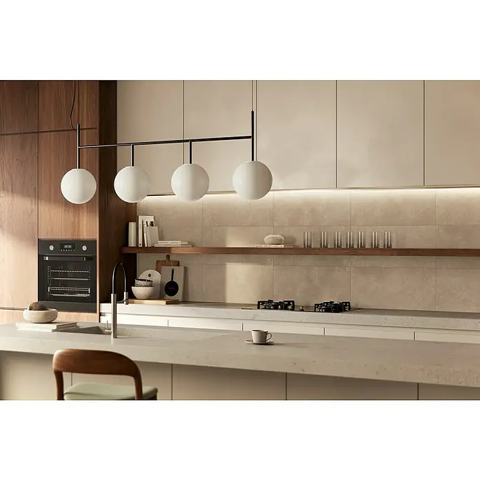 Atlas Concorde Solution Feinsteinzeugfliese Lexington - 30 x 60 cm, Dusty, Matt - Moderne Küche mit warmen Holz- und hellen Schränken, Steinoptik-Rückwand und hellen Arbeitsplatten. Mit Backofen, Gaskochfeld und auffälliger Kugelleuchte.