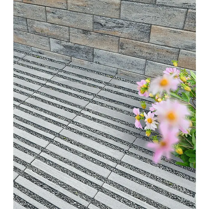 Diephaus Rasengitterstein - 30 x 30 x 6 cm, Beton, Grau - Graue rechteckige Pflastersteine mit Kiesfugen bilden einen Gartenweg neben einer Steinmauer.