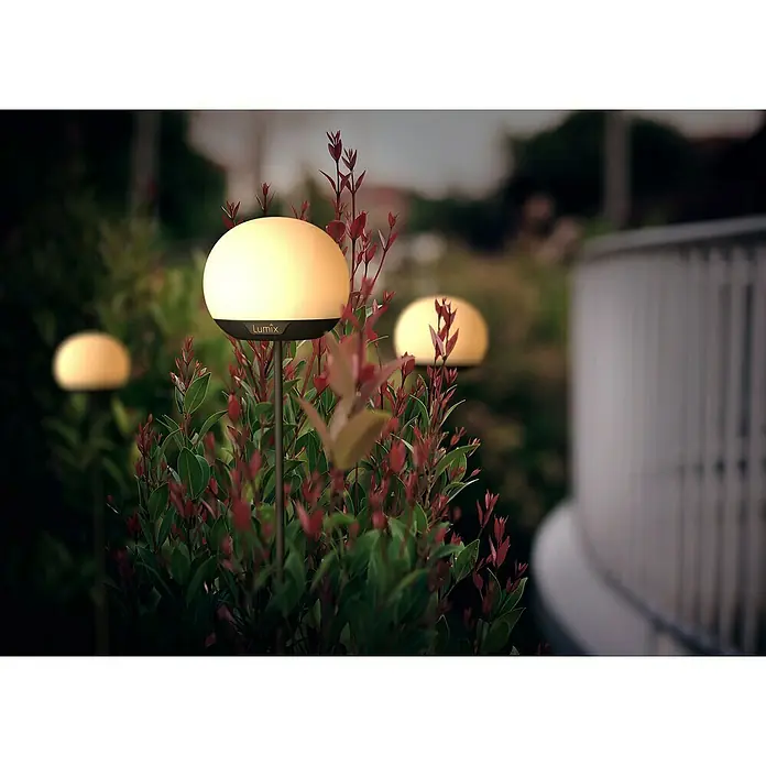 Lumix Solarleuchte Pompom - Lichtfarbe: RGB, Höhe: 100 cm, Pompom - Leuchtende, kugelförmige Lumix Gartenleuchte zwischen grünen und roten Pflanzen für Außenambiente.
