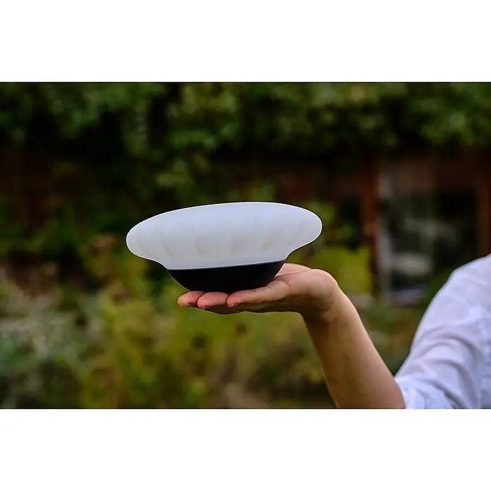 Lumix Solarleuchte Sunny - Lichtfarbe: RGB, Höhe: 100 cm, Sunny - Eine Hand hält eine weiße, durchscheinende, kuppelförmige tragbare Leuchte mit dunklem Sockel.