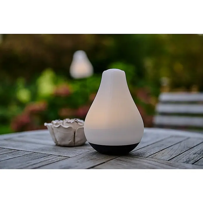 Lumix Solarleuchte Tulip - Lichtfarbe: RGB, Höhe: 100 cm, Tulip - Weiße, birnenförmige LED-Lampe mit schwarzem Sockel auf einem Holztisch im Garten.
