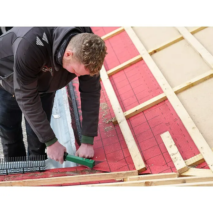 Prebena Hefthammer - Passend für: Prebena Heftklammern der Type PF 6 - 9 mm - Ein Arbeiter verwendet ein grünes Handwerkzeug auf roter Dachunterlage und Holzlatten auf einem Dach.