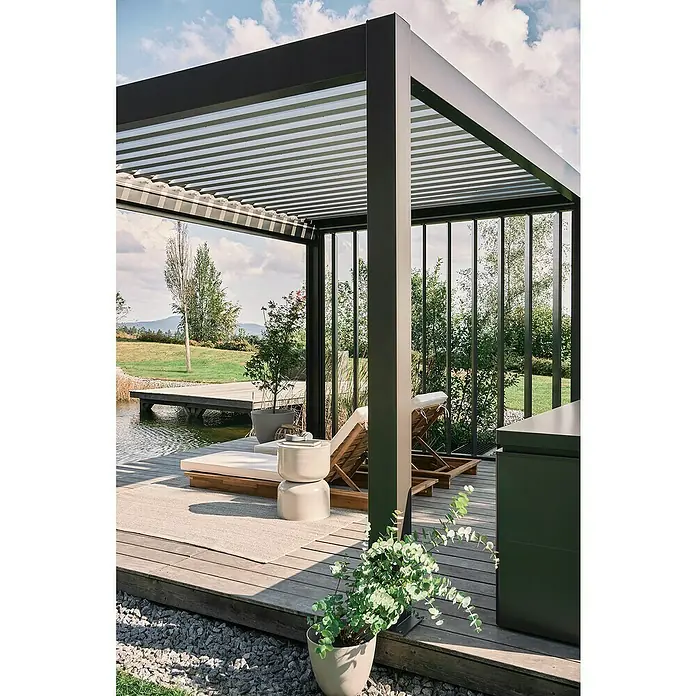 Biohort Lamellenpavillon - B x T: 404,5 x 312 cm, Dunkelgrau Metallic - Silber Metallic, Material Gestell: Stahl - Moderne dunkelgraue Bioklimapergola mit verstellbarem Lamellendach, die eine Holzterrasse mit Liegestühlen an einem Teich beschattet.