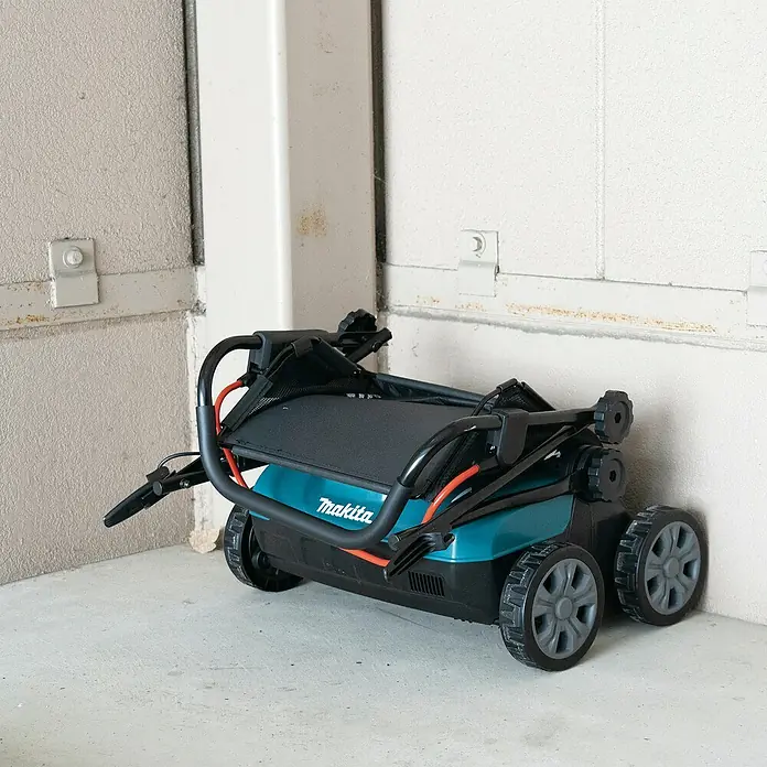 Makita LXT 18V Akku-Vertikutierer DUV320Z - Anzahl Akkus: Ohne Akku, 18 V, Arbeitsbreite: 32 cm - Geklappter türkiser und schwarzer Makita Rasenmäher mit Rädern, kompakt zur Lagerung.