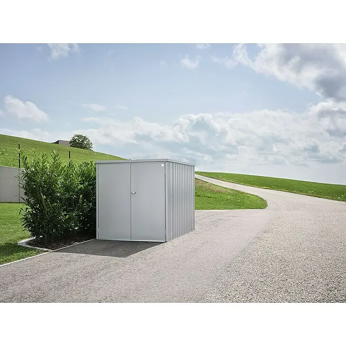 Biohort MiniGarage Fahrradgarage L - Silber-metallic, Außenbreite inkl. Dachüberstand: 145 cm, Außentiefe inkl. Dachüberstand: 203 cm - Grauer Metall-Gartenschuppen mit Doppeltüren, draußen neben einem grünen Busch und einem Kiesweg platziert.