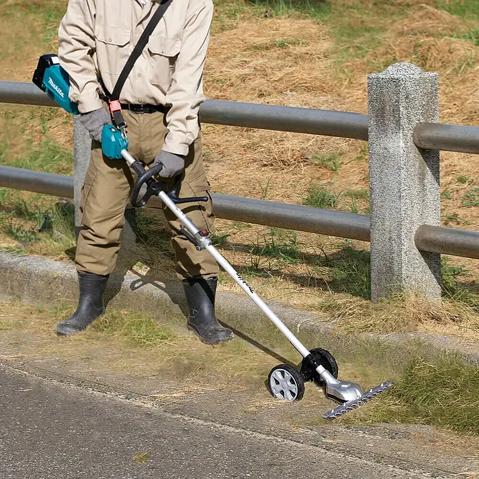 Makita Gras- & Strauchscherenaufsatz EN424MP - Passend für: DUX18, DUX60, UX01G - Person trimmt Gras am Rand mit einem silbernen Makita Rad-Heckenschneider, betrieben von einem türkisen Akku.