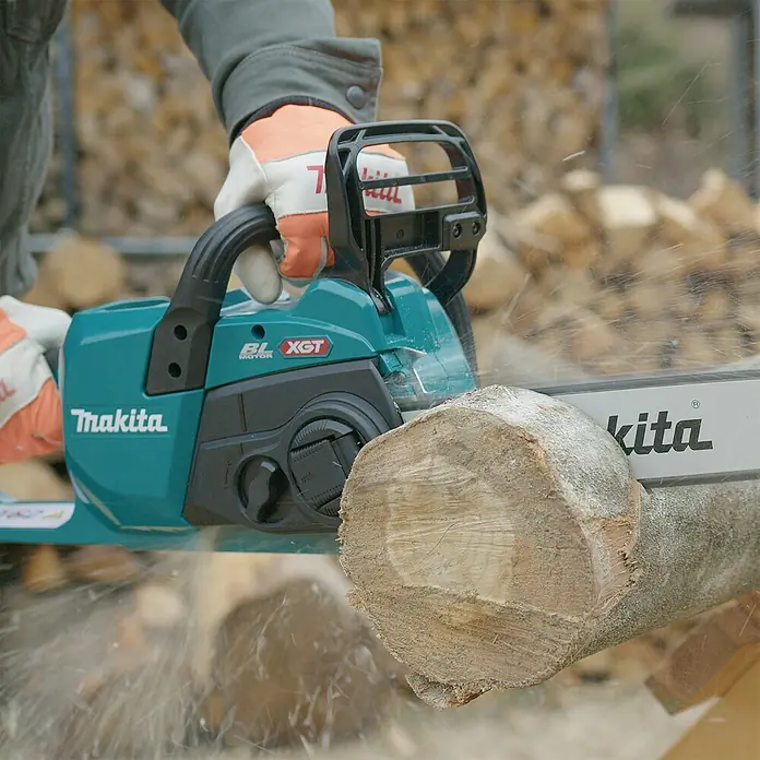 Makita XGT 40V max. Akku-Kettensäge UC022GZ - 40 V, Li-Ionen, Ohne Akku, Schwertlänge: 350 mm - Türkise Makita Kettensäge sägt aktiv ein Holzscheit, Sägespäne sind in der Luft sichtbar.