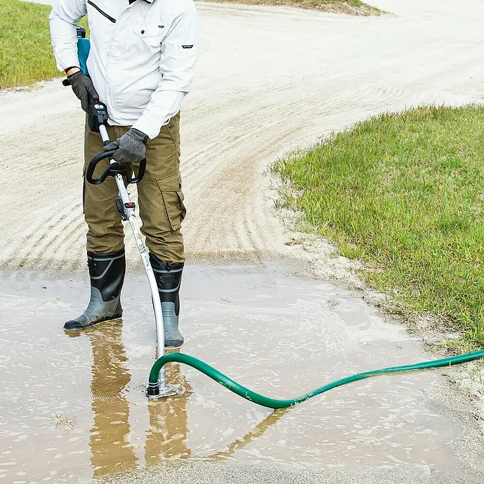 Makita Tauchpumpen-Anschlussstück PF400MP - Passend für: DUX18, DUX60, UX01G - Metallischer Wasserpumpenaufsatz für Freischneider mit grünem Schlauch, der aktiv schlammiges Wasser aus einer Pfütze pumpt.