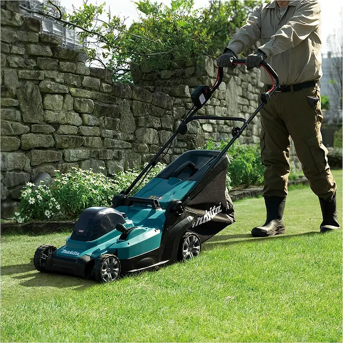 Makita XGT 40V max. Akku-Rasenmäher LM004GZ - 40 V, Ohne Akku, 8 Ah, Schnittbreite: 43 mm - Eine Person mäht grünes Gras mit einem türkis-schwarzen Makita Akku-Rasenmäher.