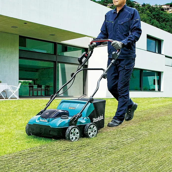 Makita XGT 40V max. Akku-Vertikutierer UV001GZ - Anzahl Akkus: Ohne Akku, 40 V, Arbeitsbreite: 38 cm - Türkiser und schwarzer Makita Rasenvertikutierer wird von einer Person zum Vertikutieren des Rasens verwendet.