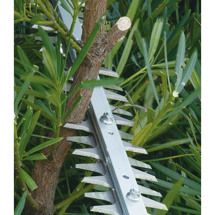 Makita XGT 40V max. Akku-Heckenschere UN001G - 40 V, Li-Ionen, Ohne Akku, Schnittlänge: 600 mm - Metallene Heckenscherenmesser schneiden einen Ast und grünes Laub.