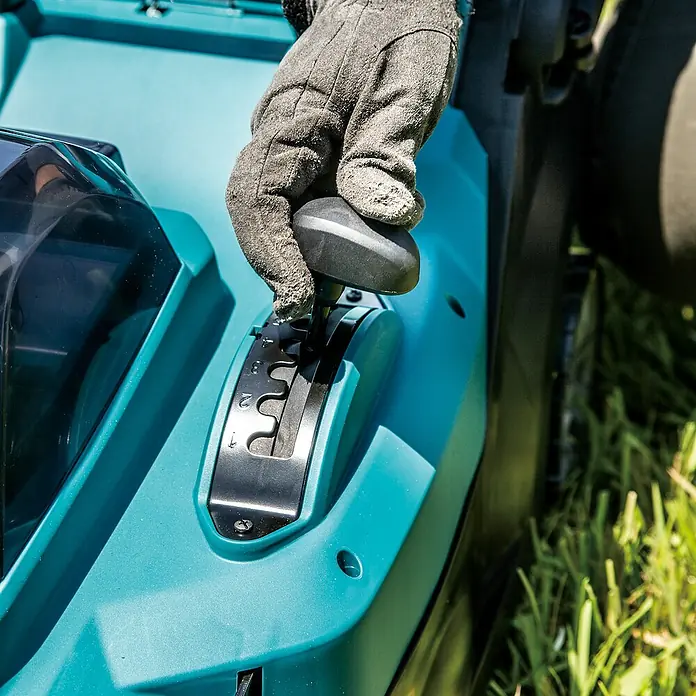 Makita XGT 40V max. Akku-Rasenmäher LM004GZ - 40 V, Ohne Akku, 8 Ah, Schnittbreite: 43 mm - Behandschuhte Hand stellt Schnitthöhenhebel an türkisfarbenem Rasenmäher ein.