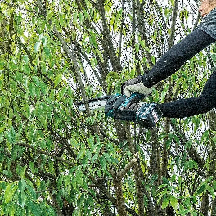 Makita XGT 40V max. Akku-Astsäge UC029GZ - 40 V, Li-Ionen, Ohne Akku, Schwertlänge: 150 mm - Hände halten eine blau-schwarze Makita Akku-Kettensäge und schneiden Äste im Baum.