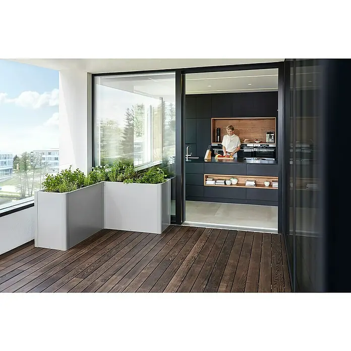 Biohort Belvedere Hochbeet Belvedere - 152 x 152 x 77 cm, Stahl, Silber Metallic - Zwei große hellgraue Metallpflanzgefäße mit Kräutern auf einem Holz-Balkon neben einer Küche.