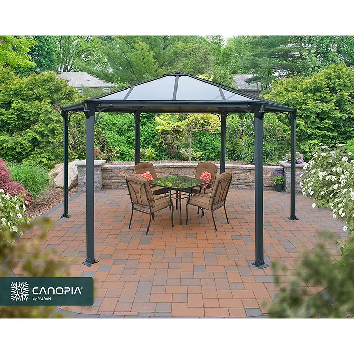 Palram – Canopia Standard-Pavillon Monaco - B x T: 390 x 450 cm, Farbe Gestell: Anthrazit, Aluminium - Dunkelgrauer Pavillon mit transparentem Dach auf einer Terrasse, mit Esstisch und Stühlen für Mahlzeiten im Freien.