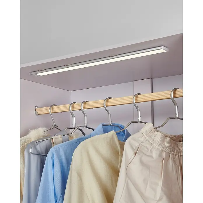 Eglo Lámpara LED bajo mueble Benasco - L x An x Al: 57 x 4 x 0,9 cm - Barra de luz LED plateada con sensor de movimiento montada dentro de un armario, iluminando la ropa en una barra de madera.