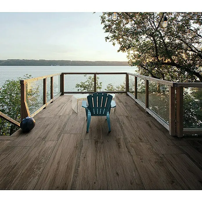 Terrassenfliese Essenze 2.0 - 40 x 120 x 2 cm, Musk, Matt - Holzoptik-Terrassenbelag in rustikalem Braunton, auf einer Terrasse mit Seeblick verlegt.
