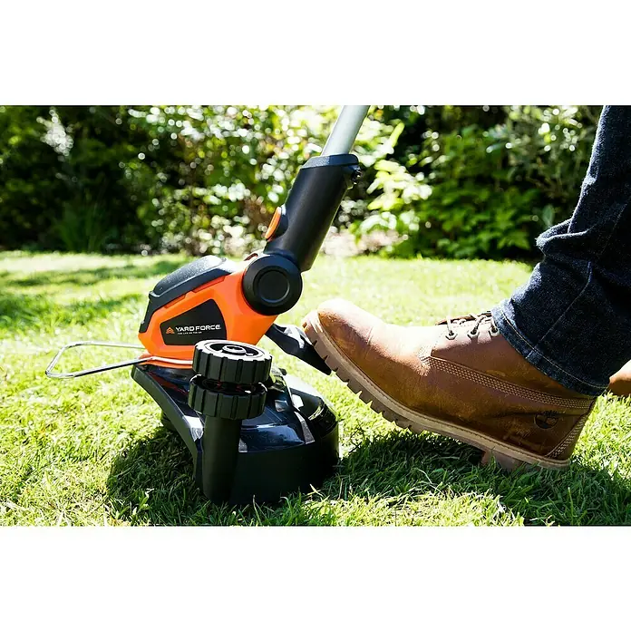 Yard Force Elektro-Rasentrimmer LM F23 iFlex Urban - 350 W, Schnittbreite Faden: 25 cm - Orangener und schwarzer Yard Force Rasentrimmer auf Rasen, mit einem Fuß in einem braunen Stiefel darauf.