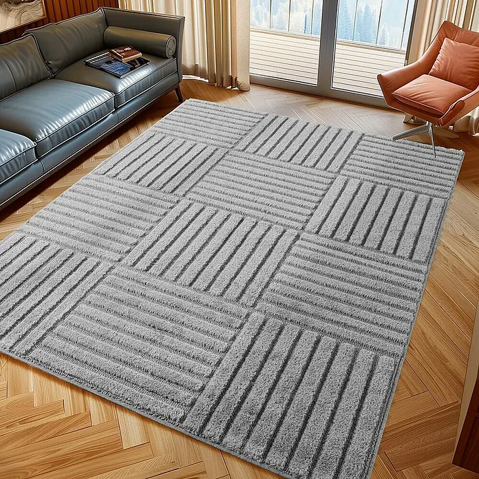 Kurzflorteppich Art 1123 - Silber, 200 x 140 cm, 100 % Polypropylen - Hellgrauer Teppich mit strukturiertem geometrischem Streifenmuster auf Holzboden in einem Wohnzimmer.
