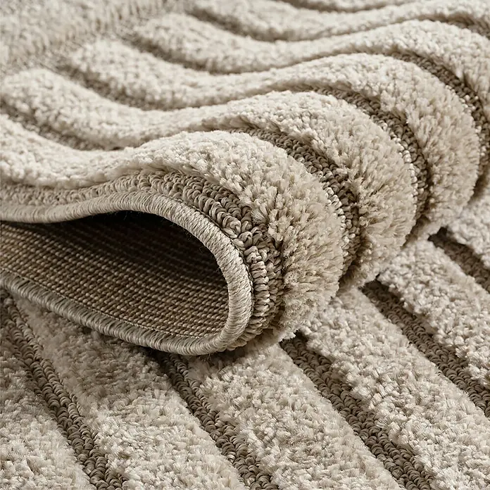 Kurzflorteppich Art 1123 - Beige, Durchmesser: 80 cm, 100 % Polypropylen - Beiger Plüschteppich mit wellenförmiger Textur, zeigt weichen Flor und gewebte Unterseite im gefalteten Zustand.