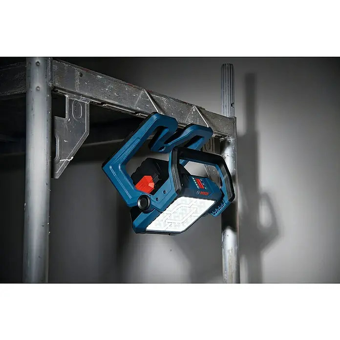 Bosch Professional AMPShare 18V LED-Akkustrahler GLI 18V-5000 C - 18 V, Ohne Akku, Lichtstrom: 5.000 lm - Blau-schwarze Bosch LED-Arbeitsleuchte, beleuchtet, hängt an einem Metallgerüst.