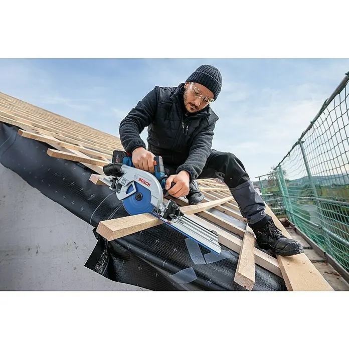 Bosch Professional Führungsschiene FSN 300 X - L x B x H: 643 x 228 x 49 mm - Mann schneidet Holz auf einem Dach mit einer blauen und grauen Bosch Akku-Kreissäge.