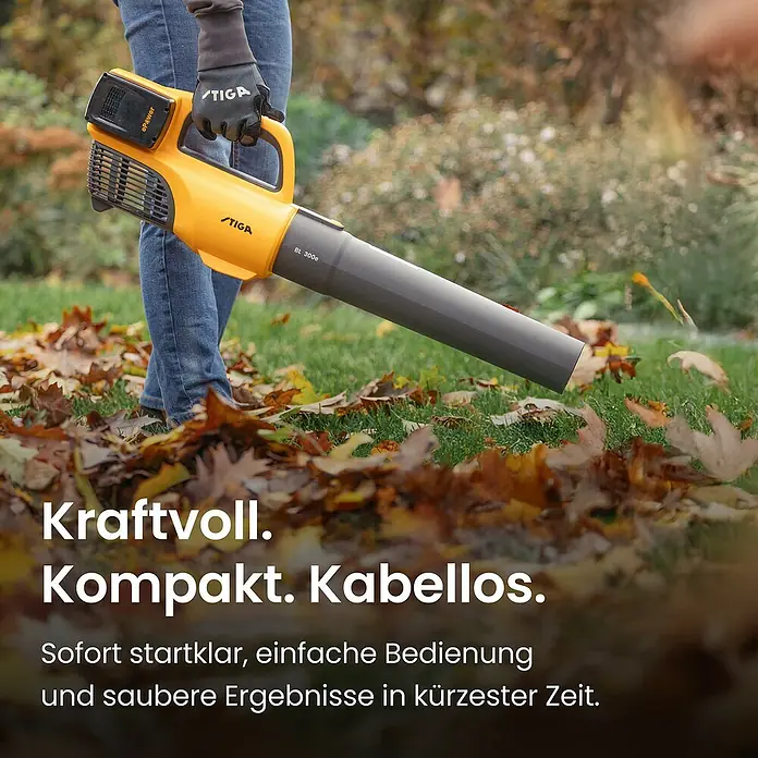 Stiga Akku-Laubbläser BL 300 E - 20 V, 2 Akkus, 4 Ah, Blasgeschwindigkeit: 42 m/s - Person hält einen gelben und dunkelgrauen STIGA BL 300e Laubbläser, der fallendes Laub im Garten bläst.