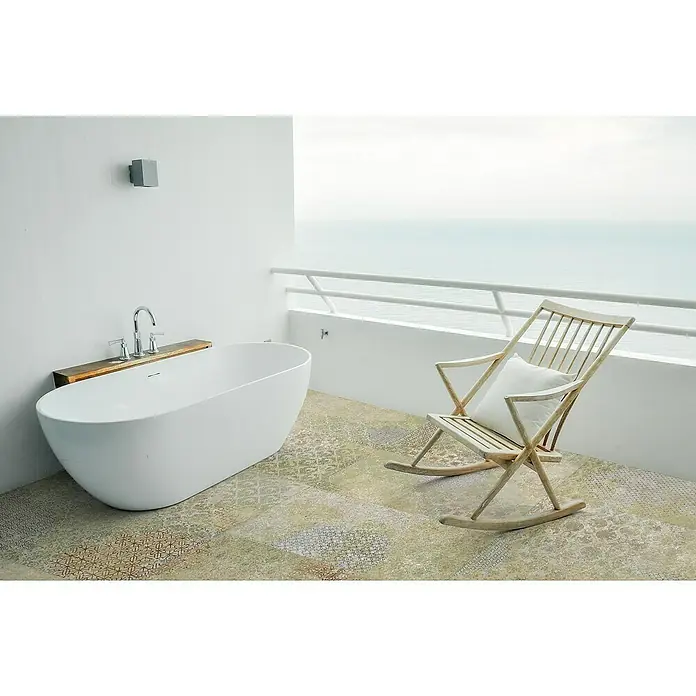 Bohemian Feinsteinzeugfliese - 59,55 x 59,55 cm, Blend, Matt - Weiße freistehende Badewanne auf einem gefliesten Balkon mit Meerblick, neben einem Holzschaukelstuhl.