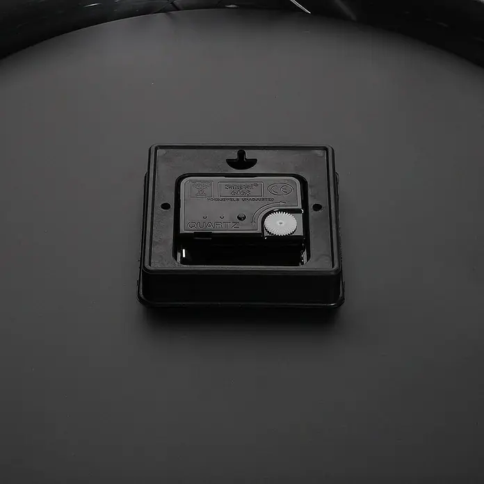 Versa Reloj de pared - Diámetro: 35 cm, Blanco/Negro, Clásico - Mecanismo de reloj de cuarzo cuadrado negro con un engranaje blanco visible para ajustar la hora.