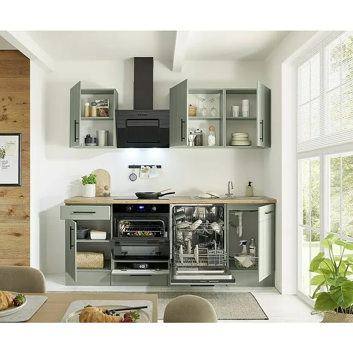 Respekta Küchenzeile Anton Typ 2 - Breite: 220 cm, Schilfgrün, Mit Elektrogeräten - Salbeigrüne Küche mit Holztheke, integrierten Geräten und offener Spülmaschine mit Geschirr.