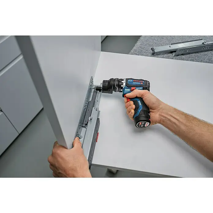 Bosch Professional AMPShare 18V Akku-Bohrschrauber-Set GSR 12V-32 FC 2x2,0AH - 12 V, 2 Akkus, 32 Nm, 9 -tlg. - Eine Person benutzt einen blau-schwarzen Bosch Akkuschrauber, um eine Schubladenschiene an einem weißen Schrank zu montieren.