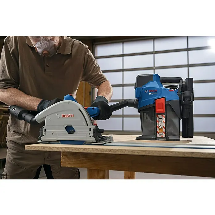 Bosch Professional AMPShare 18V Akku-Staubsauger GAS 18V-6 LS - 18 V, Behältervolumen: 4,5 l - Ein Arbeiter sägt mit einer Bosch Tauchsäge, die an einen blauen Bosch Sauger angeschlossen ist.