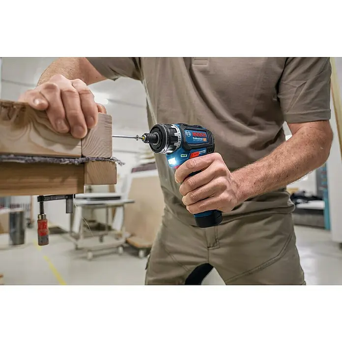 Bosch Professional AMPShare 18V Akku-Bohrschrauber-Set GSR 12V-32 FC 2x2,0AH - 12 V, 2 Akkus, 32 Nm, 9 -tlg. - Person benutzt blauen und schwarzen Bosch Akku-Schrauber, um Schraube in Holzbretter zu drehen.