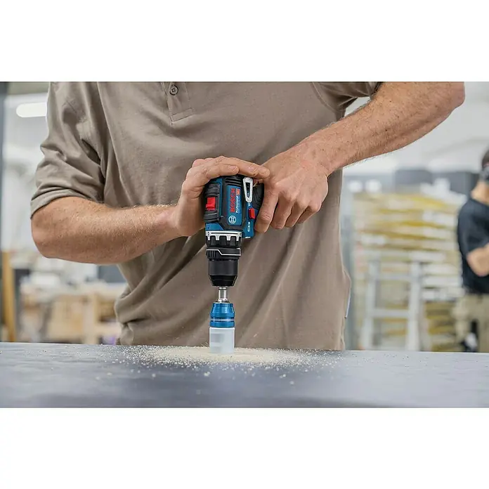 Bosch Professional AMPShare 18V Akku-Bohrschrauber-Set GSR 12V-32 FC 2x2,0AH - 12 V, 2 Akkus, 32 Nm, 9 -tlg. - Bosch Akkubohrschrauber mit blau-weißem Staubfangaufsatz bohrt in eine Oberfläche, Sägespäne sichtbar.