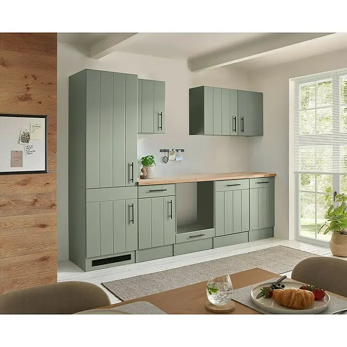 Respekta Küchenleerblock Anton - Breite: 280 cm, Schilfgrün, Ohne Elektrogeräte - Moderne Küche mit salbeigrünen Schränken, schwarzen Griffen und hellen Holz-Arbeitsplatten in einem hellen Raum.