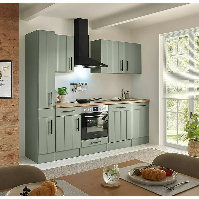 Respekta Küchenzeile Anton Typ 1 - Breite: 250 cm, Schilfgrün, Mit Elektrogeräten - Moderne Küche mit hellgrünen Schränken, Holz-Arbeitsplatte, integriertem Backofen und schwarzer Dunstabzugshaube.