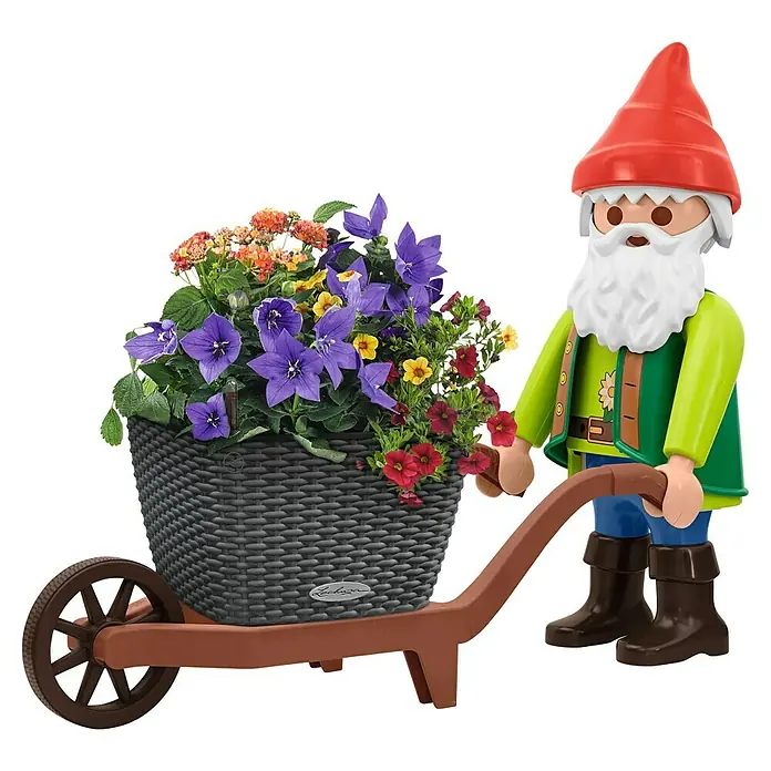 Lechuza Dekofigur XXL Gartenzwerg - L x B x H: 27,5 x 33,4 x 68 cm, Kunststoff - Playmobil-Gartenzwerg mit rotem Hut und grüner Weste schiebt braune Schubkarre mit grauem Flechtkübel voller lila, gelber, oranger und roter Blumen.