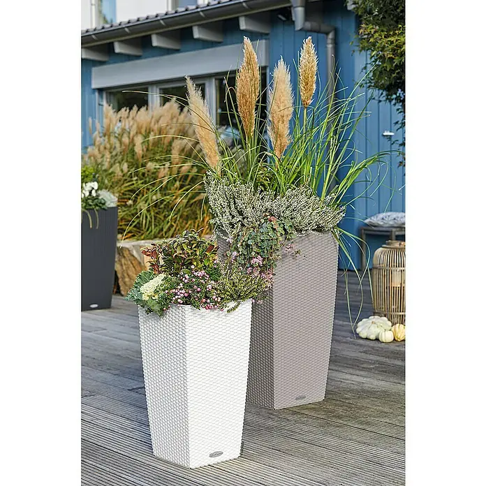 Lechuza Cottage Pflanzsäule eckig Cubico 40 - Außenmaß (L x B x H): 39,5 x 39,5 x 75,5 cm, Kunststoff, Sandbraun - Zwei hohe, rechteckige Pflanzgefäße mit Geflechtstruktur, ein weißes kleineres und ein graues größeres, bepflanzt auf einer Holzterrasse.