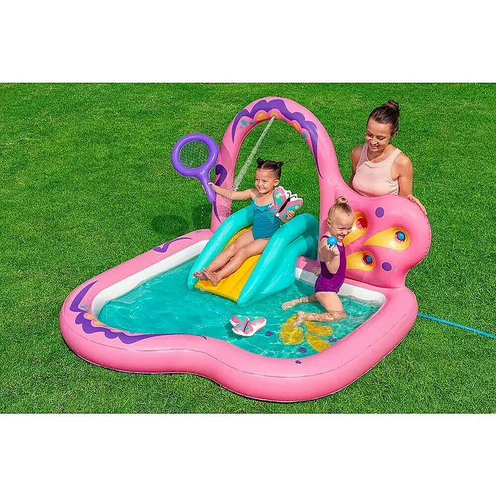 Bestway Planschbecken Wasserspielcenter Schmetterling - 180 x 180 x 117 cm - Zwei Kinder spielen in einem pink-lila aufblasbaren Wasserspielcenter mit Rutsche und Sprühbogen, beaufsichtigt von einer Erwachsenen.