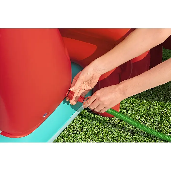Bestway Planschbecken Kleine Meerjungfrau - 221 x 193 x 117 cm - Hände verbinden einen grünen Gartenschlauch mit einem roten Anschluss an einem rot-blauen aufblasbaren Pool.