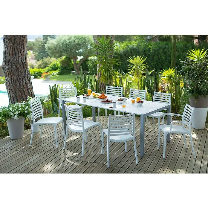 Grosfillex Stapelsessel Set Sunday - 4 Stk., Polypropylen, Stapelbar, Weiß, B x T x H: 59 x 56 x 84 cm - Weiße Lattenstühle und ein weißer Esstisch mit grauen Beinen auf einer Holzterrasse, für eine Mahlzeit im Freien gedeckt.