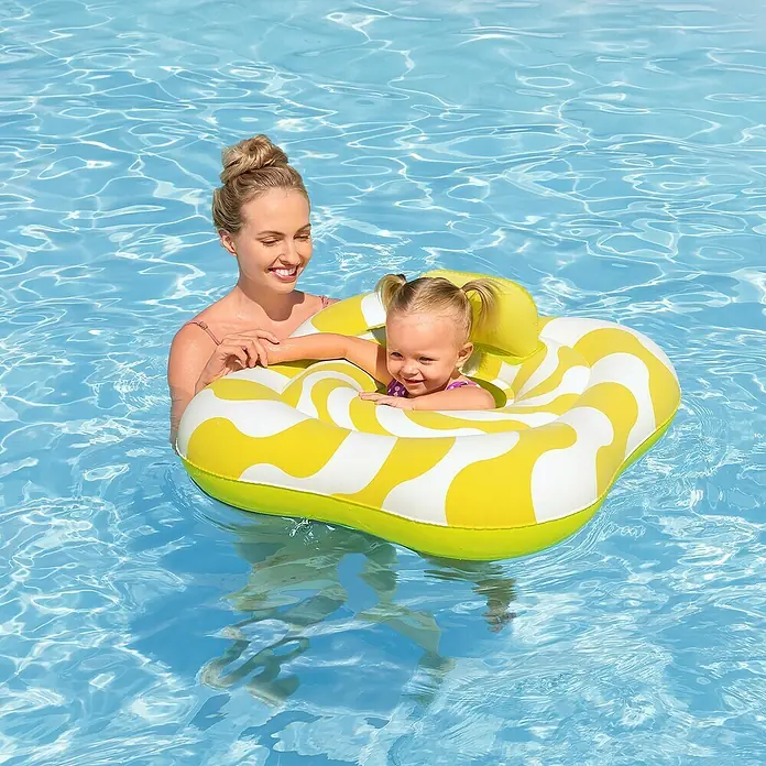 Bestway Schwimmsitz Samtoberfläche - Gelb, 4 Luftkammern - Gelb-weiß gemusterter aufblasbarer Pool-Schwimmring mit Kind darin, im Pool mit einer Erwachsenen.