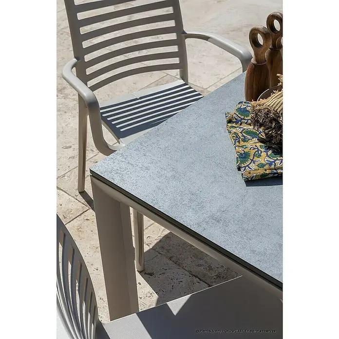 Grosfillex Stapelsessel Set Sunday - 4 Stk., Polypropylen, Stapelbar, Beige, B x T x H: 59 x 56 x 84 cm - Grauer Outdoortisch mit strukturierter Platte und hellgrauen Lattenstühlen auf einer Terrasse.