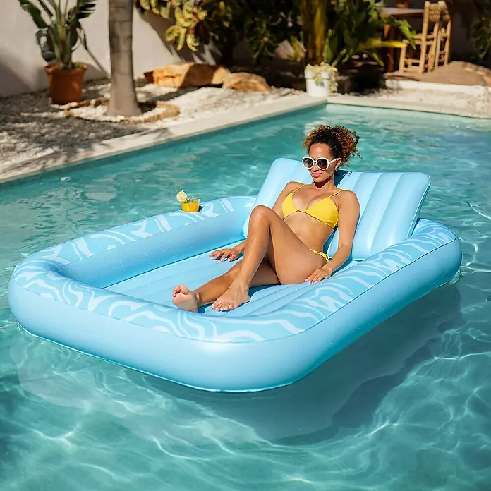 Bestway Luftmatratze Tanning Lounge - L x B: 1,37 x 2,03 m - Blauer aufblasbarer Pool-Schwimmer mit Wellenmuster, der von einer Frau im Pool benutzt wird.