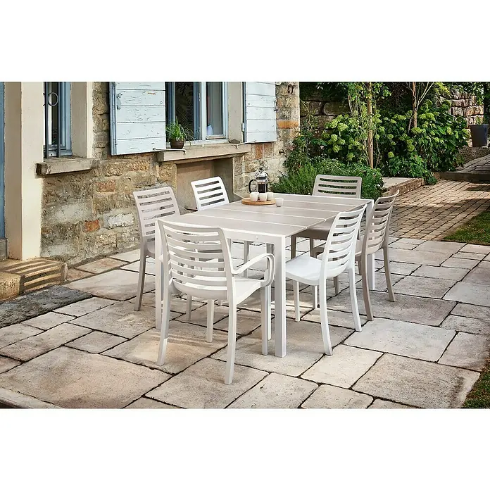 Grosfillex Stapelstuhl Set Slat - 4 Stk., Polypropylen, Stapelbar, Beige, B x T x H: 53 x 58 x 88 cm - Helles Outdoor-Esstischset mit Tisch und Stühlen auf einer Steinterrasse.