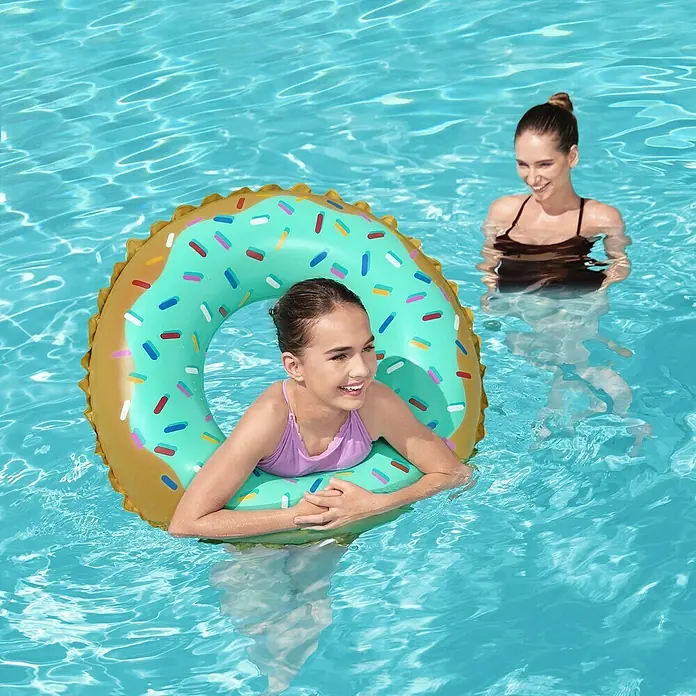 Bestway Schwimmring Donut - Braun/Türkis - Mädchen in einem türkisfarbenen Donut-Schwimmreifen mit bunten Streuseln im Pool, mit einer Erwachsenen daneben.