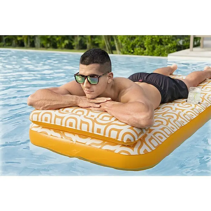 Bestway Luftmatratze mit Samtoberfläche - L x B: 77,5 x 169 cm - Mann entspannt auf einer gelb-weiß gemusterten aufblasbaren Poolliege mit Getränkehalter.