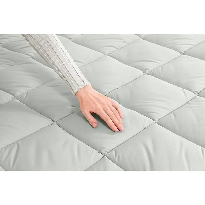 Bestway Luftbett - L x B x H: 203 x 152 x 51 cm, Dunkelbraun, Integrierte Luftpumpe - Eine Hand drückt sanft auf einen weichen, weißen gesteppten Matratzenschoner und hebt seine plüschige Textur hervor.