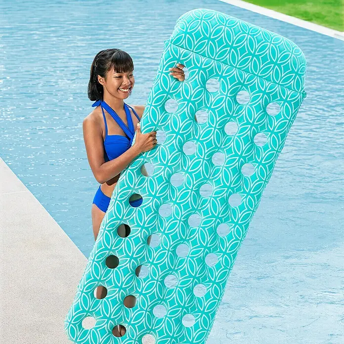 Bestway Luftmatratze Comfort Plush - L x B: 65 x 171 cm - Frau im Pool hält eine große türkise aufblasbare Schwimmmatratze mit weißem geometrischem Muster und Löchern.