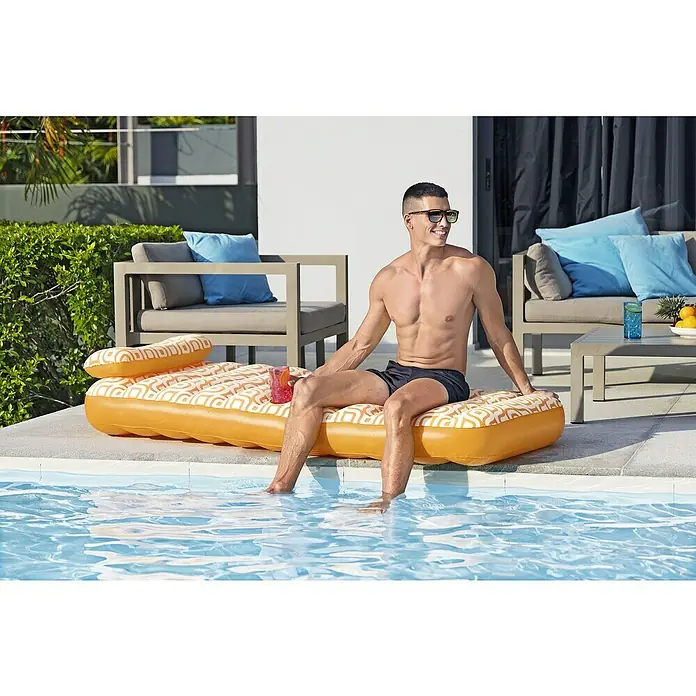 Bestway Luftmatratze mit Samtoberfläche - L x B: 77,5 x 169 cm - Ein orangefarbener aufblasbarer Pool-Schwimmer mit weißem geometrischem Muster, der von einem Mann mit den Füßen im Wasser benutzt wird.